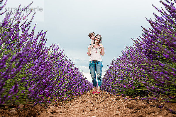 Mutter und Tochter spazieren im Sommer zwischen Lavendelfeldern