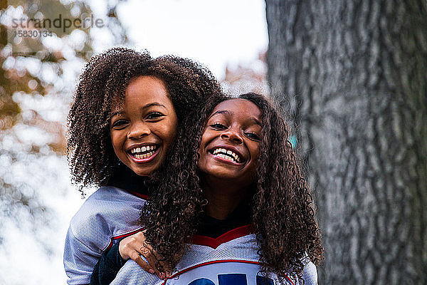 Porträt von fröhlichen Schwestern in Sportkleidung im Park