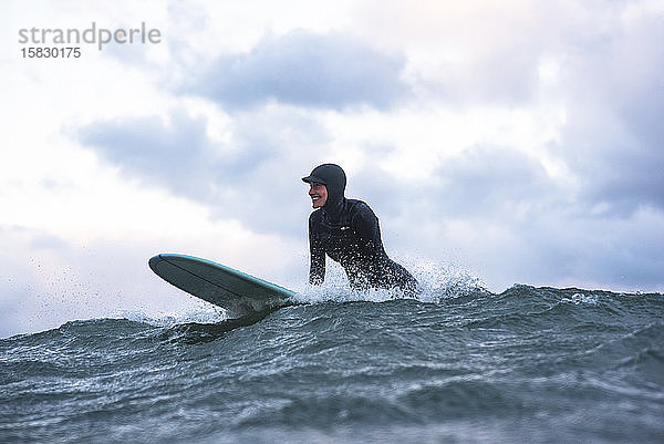 Frau genießt an einem windigen Tag das Surfen im Winter