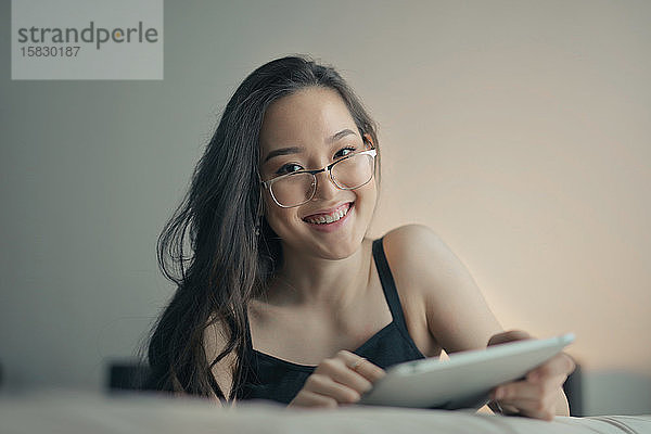 junge asiatische frau studiert zu hause mit tablette