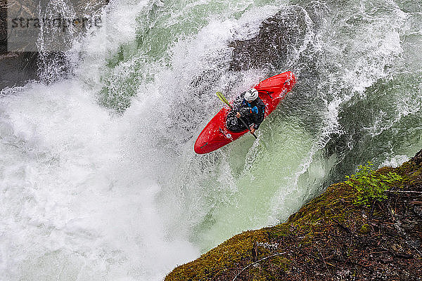 Ein Wildwasser-Kajakfahrer paddelt über einen Wasserfall auf dem Fluss Cheakamus.