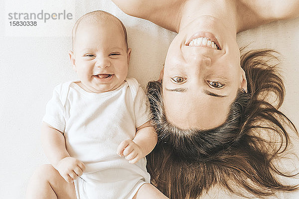 Mutter und neugeborener Sohn liegen ausgestreckt im Bett und lachen