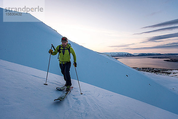 Mann Skitourenskifahren in Island bei Sonnenaufgang