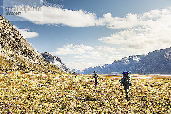 Zwei Bergsteiger durchqueren die arktische Tundra am Akshayuk-Pass.