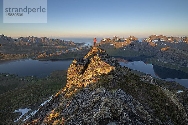 Männlicher Wanderer überblickt die Berglandschaft des Selfjord-Gebiets vom Gipfel des Kitind aus  MoskenesÃ¸y  Lofoten-Inseln  Norwegen