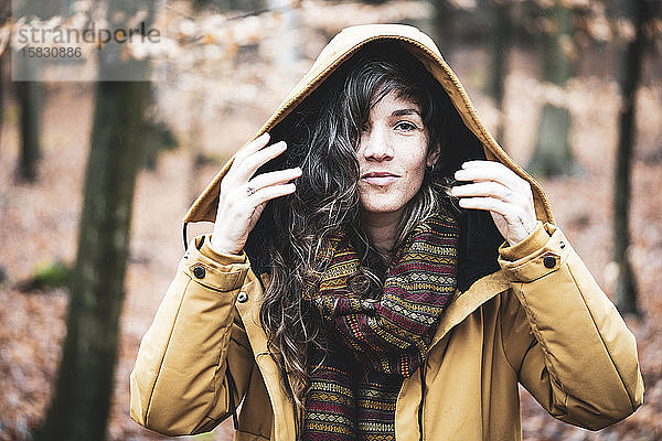 natürliches Mädchen in Winterjacke lächelt im goldbronzenen Herbstwald