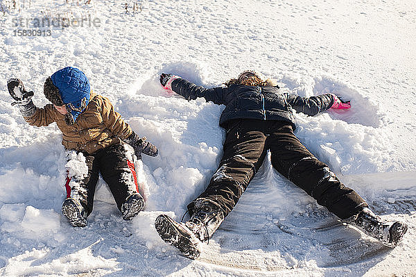 Bruder und Schwester spielen im Schnee im Vorgarten