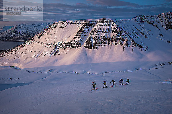 Personengruppe beim Skilanglauf bei Sonnenaufgang in Island