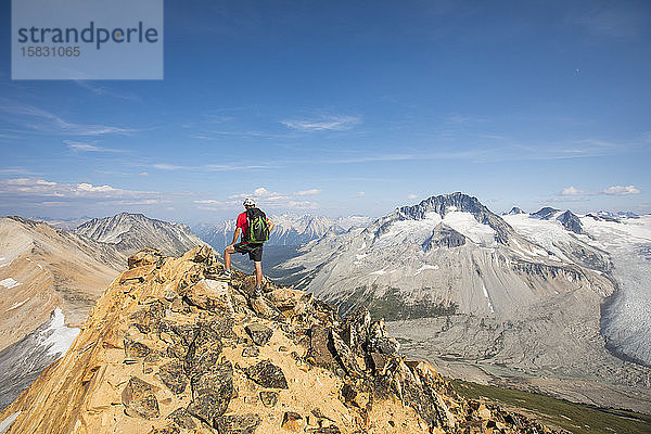 Rucksacktourist auf Berggipfel stehend.