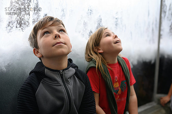 Zwei Kinder schauen staunend zu Wellen und Wasser auf