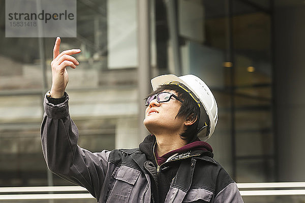 Bauingenieur mit Helm vor einem Gebäude