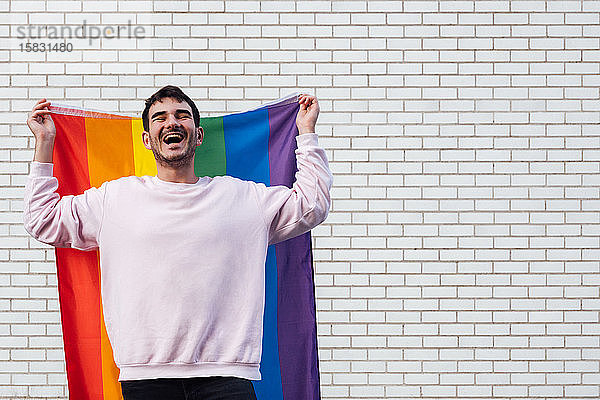 Glücklicher schwuler Mann mit Regenbogenfahne