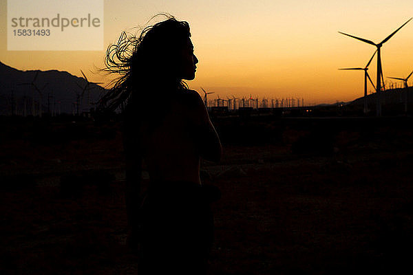 Silhouette einer Frau vor dem Windpark bei Sonnenuntergang