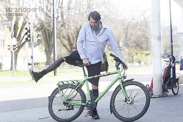 älterer Mann mit Beinprothese wird Fahrrad fahren