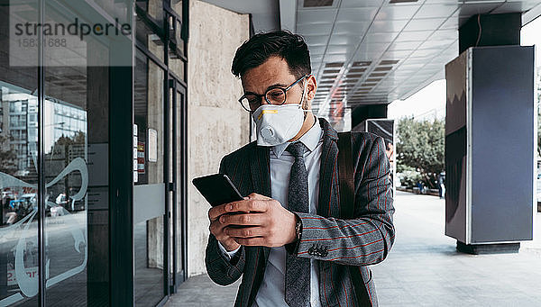 Geschäftsmann mit schützender Gesichtsmaske beim Telefonieren auf der Straße in der Stadt.