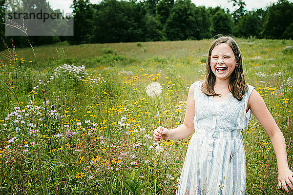 Mädchen lacht beim Pflücken von Wildblumen auf einem Feld