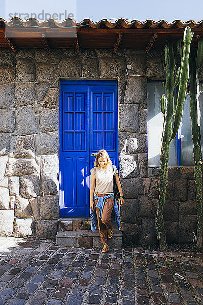 Eine junge Frau steht an einer alten blauen Tür in Cusco  Peru