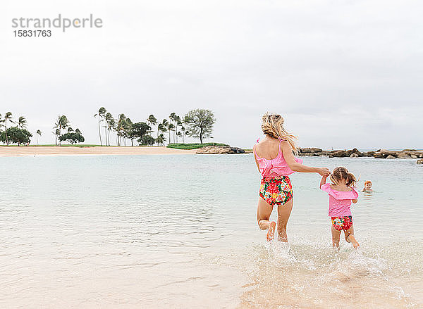 Mutter und Tochter spielen im Ozean