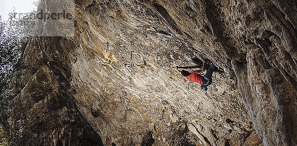 Kletterer  der eine harte Sportkletterroute in einer Höhle schickt.