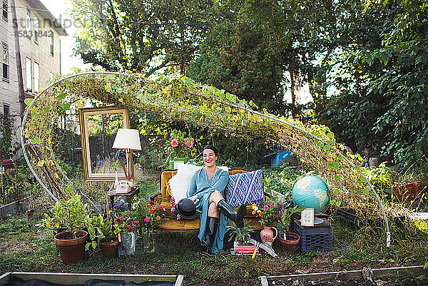 glückliche Frau auf einer alten Couch in einem Garten