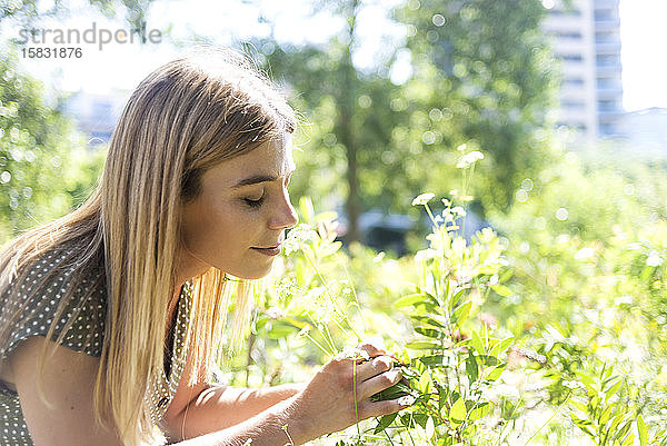 Junge blonde Frau redaktionell geschlossen duftende Blumen in einem Park