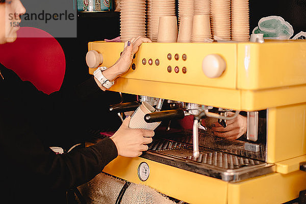 Weibliche Baristain bereitet Tee mit der Kaffeemaschine zu