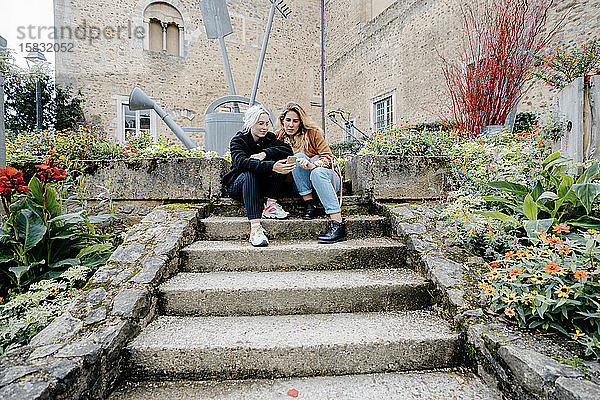 Junge Frauen mit ihrem Smartphone saßen in einer französischen Stadt auf einer Treppe