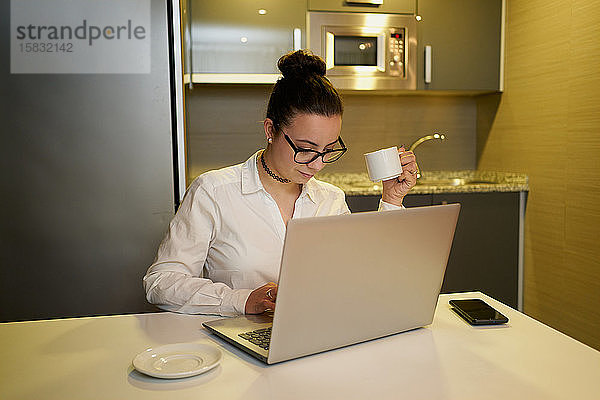 Junge Frau  die abends mit dem Laptop arbeitet