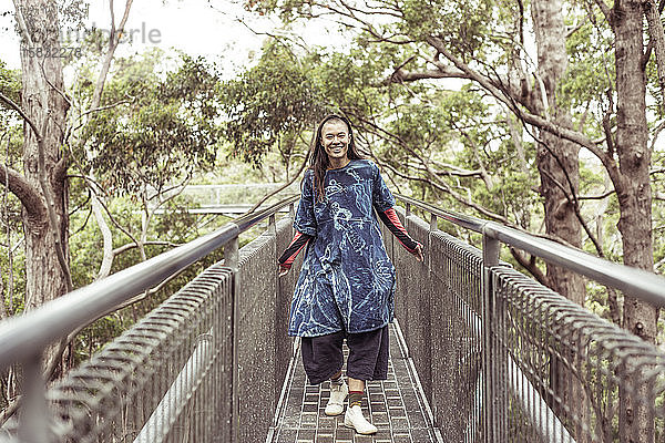 gemischtrassige asiatische Queer-Frau lächelt und lacht beim Spaziergang durch die Baumwipfel