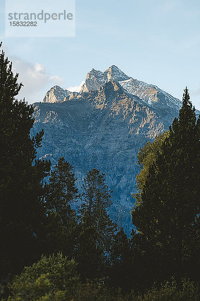 Ein Berggipfel wird von goldenen Strahlen der untergehenden Sonne beleuchtet.