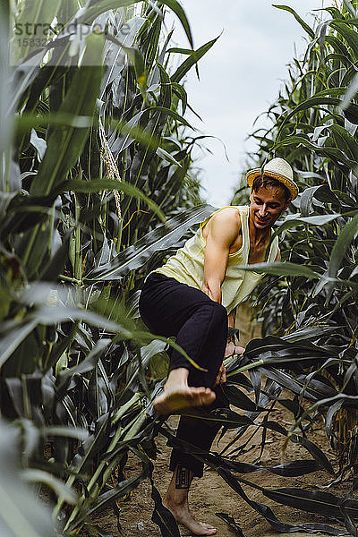 Porträt eines Bauern mit Hut auf einer grünen Wiese  der den Mais aufhebt.