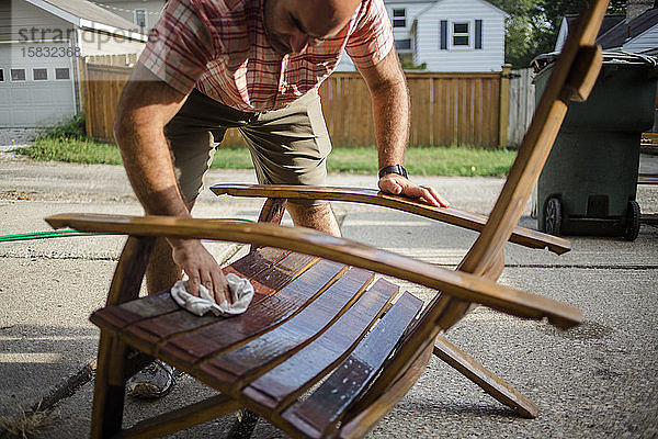 Ein Handwerker poliert draußen einen handgefertigten Holzstuhl