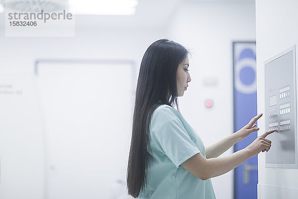 asiatische Krankenschwester bei der Kontrolle einer Schalttafel
