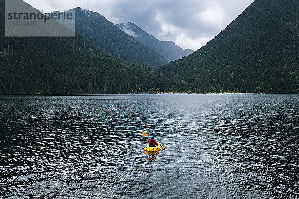 Person im Kajak  die auf dem See in Richtung Berge paddelt