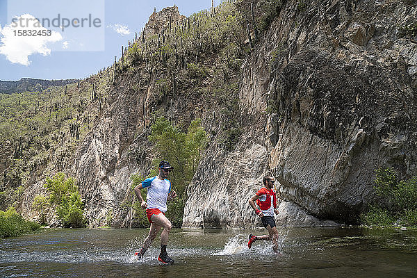 Zwei Männer überqueren einen Fluss auf dem Grund eines Canyons in Mexiko