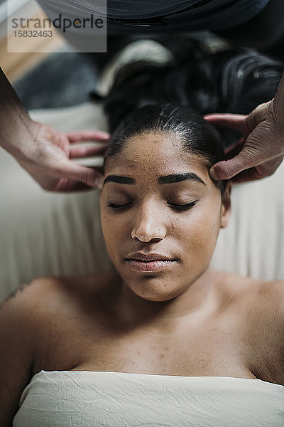 afroamerikanische Frau erhält Kopfhautmassage von Therapeut