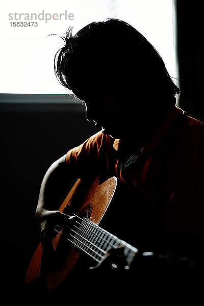 Silhouette eines Gitarre spielenden Jungen