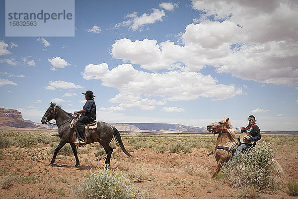 Cowboys reiten über eine offene Ebene in der Nähe des Monument Valley  Arizona