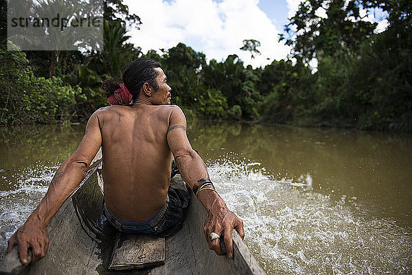 Ein Mann des Mentawai-Stammes sitzt im Kanu und fährt auf dem Fluss