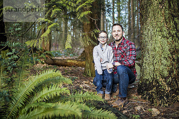 Der Vater hält seinen hübschen Sohn im Wald.