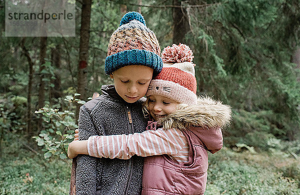 Umarmung der Geschwister beim Spielen im Wald