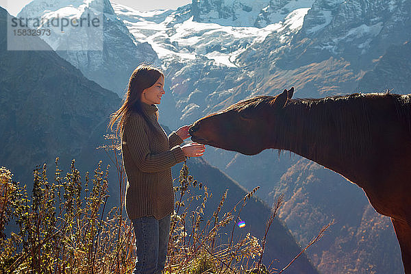 Mädchen mit einem Pferd im Hintergrund der Berge