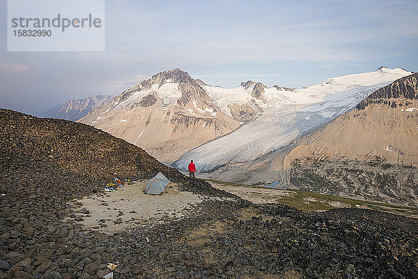 Wanderer steht neben dem Zelt auf dem Berggipfel.