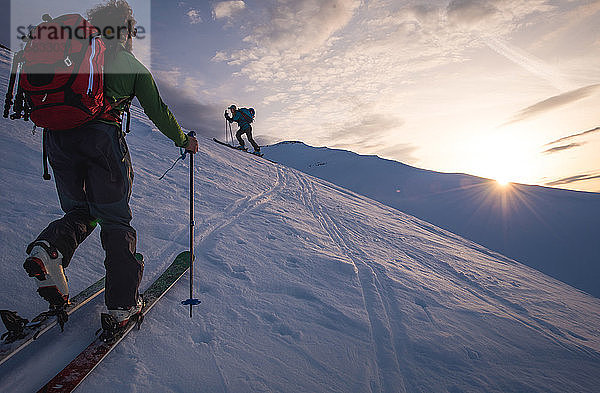 Zwei Personen bei Sonnenaufgang beim Skilanglauf in Island