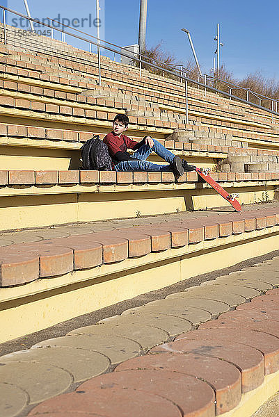 Junger Teenager sitzt auf einer Treppe im Freien und schaut an einem sonnigen Tag weg