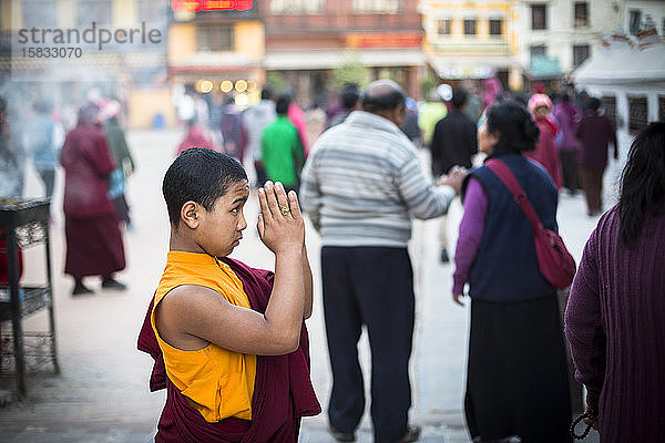 Ein junger Mönch betet an der Boudhanath-Stupa in Kathmandu (Nepal).