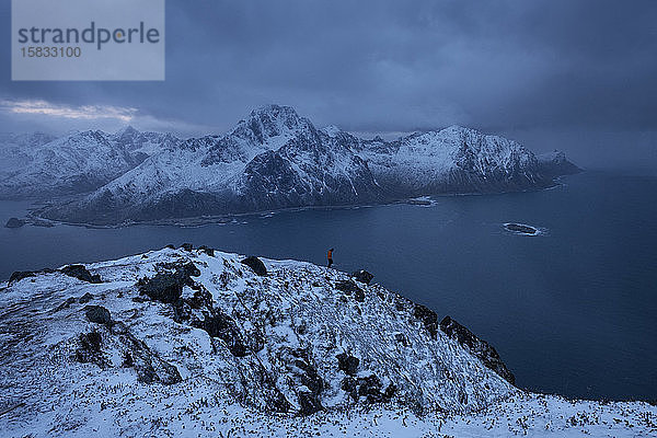 Wanderer auf dem Wintergipfel von OffersÃ¸ykammen Berggipfel mit FlakstadÃ¸y im Hintergrund  Lofoten-Inseln  Norwegen