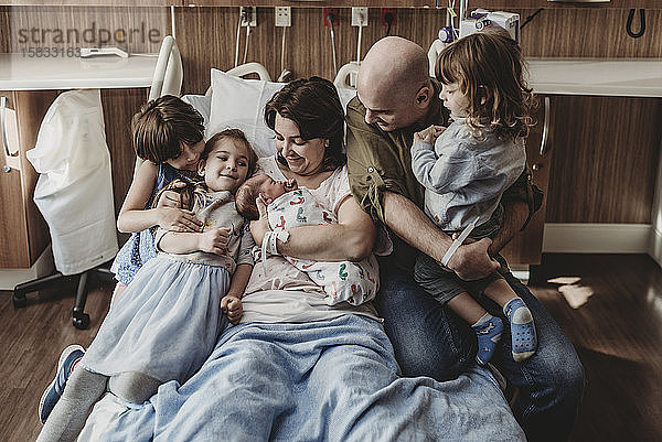 Mittelansicht der ganzen Familie  die den neugeborenen Sohn im Krankenhaus hält