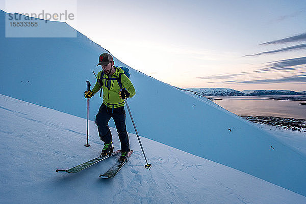 Mann beim Skilanglauf in Island bei Sonnenaufgang