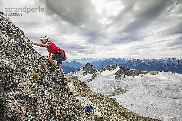 Zwei Bergsteiger klettern eine Felsklippe in den Bergen hinauf.
